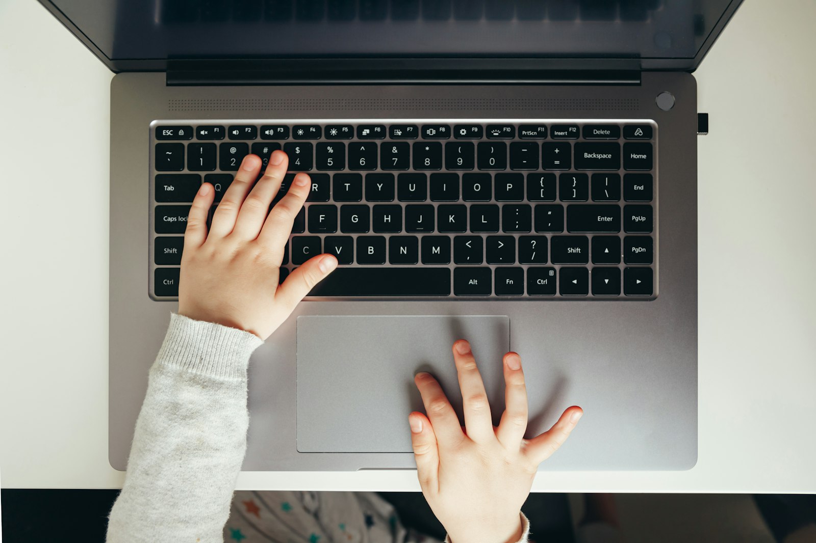 A child's hands typing on a laptop keyboard