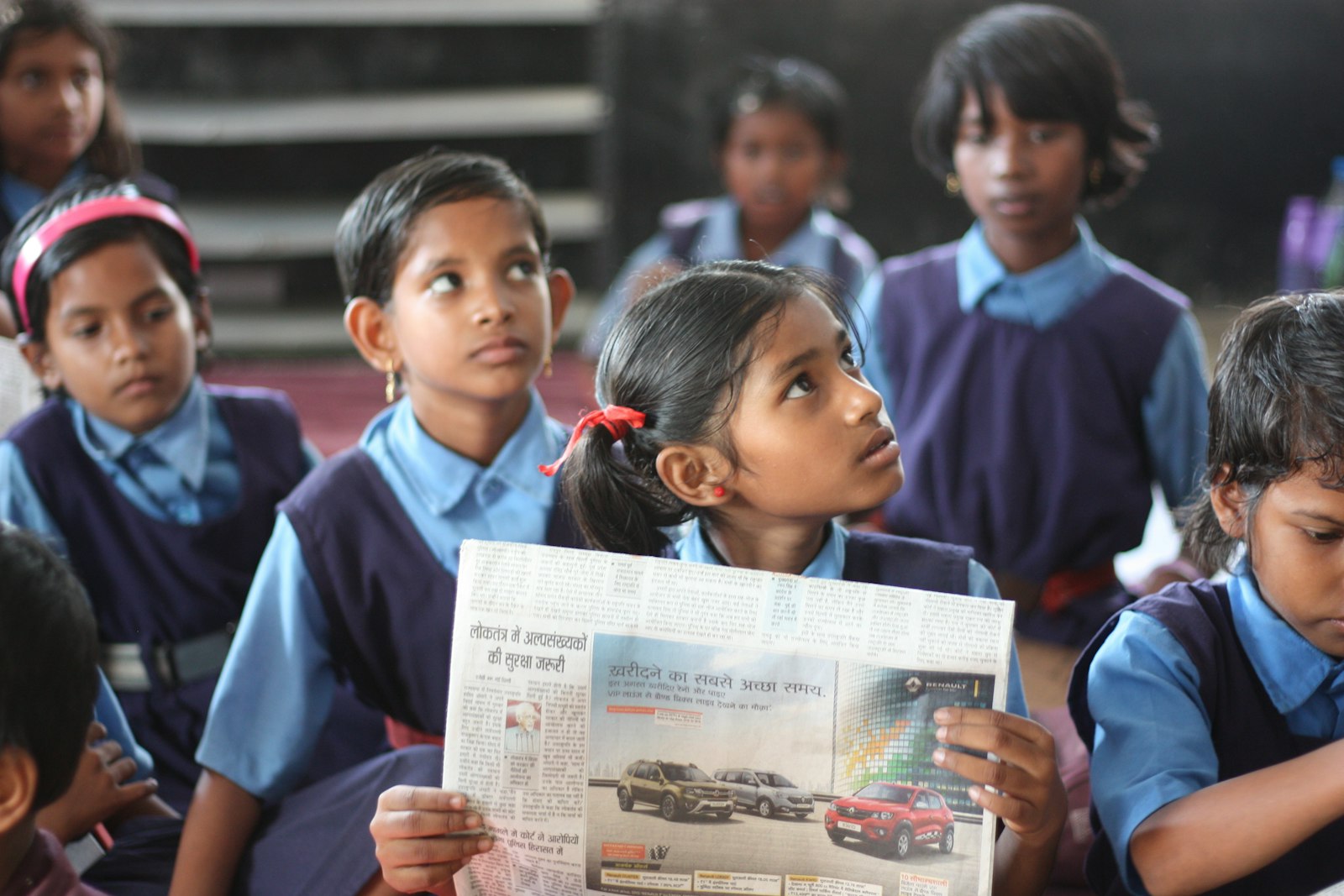 A girl reading a newspaper.