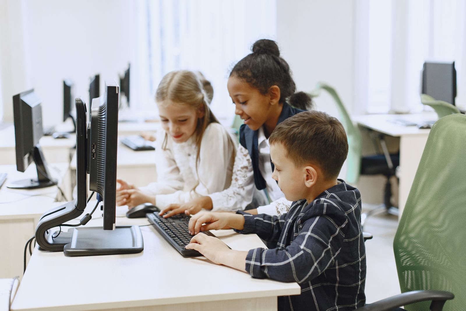 Children working together on computers in a school computer lab.