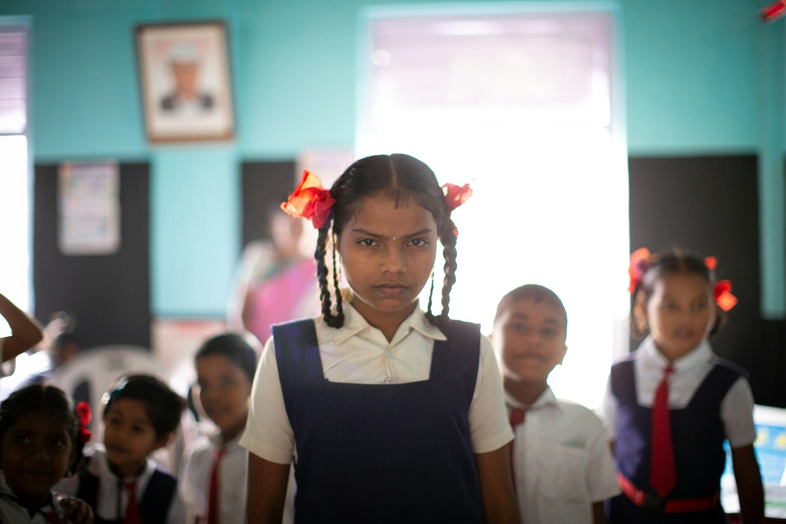A schoolgirl in uniform standing in class with classmates