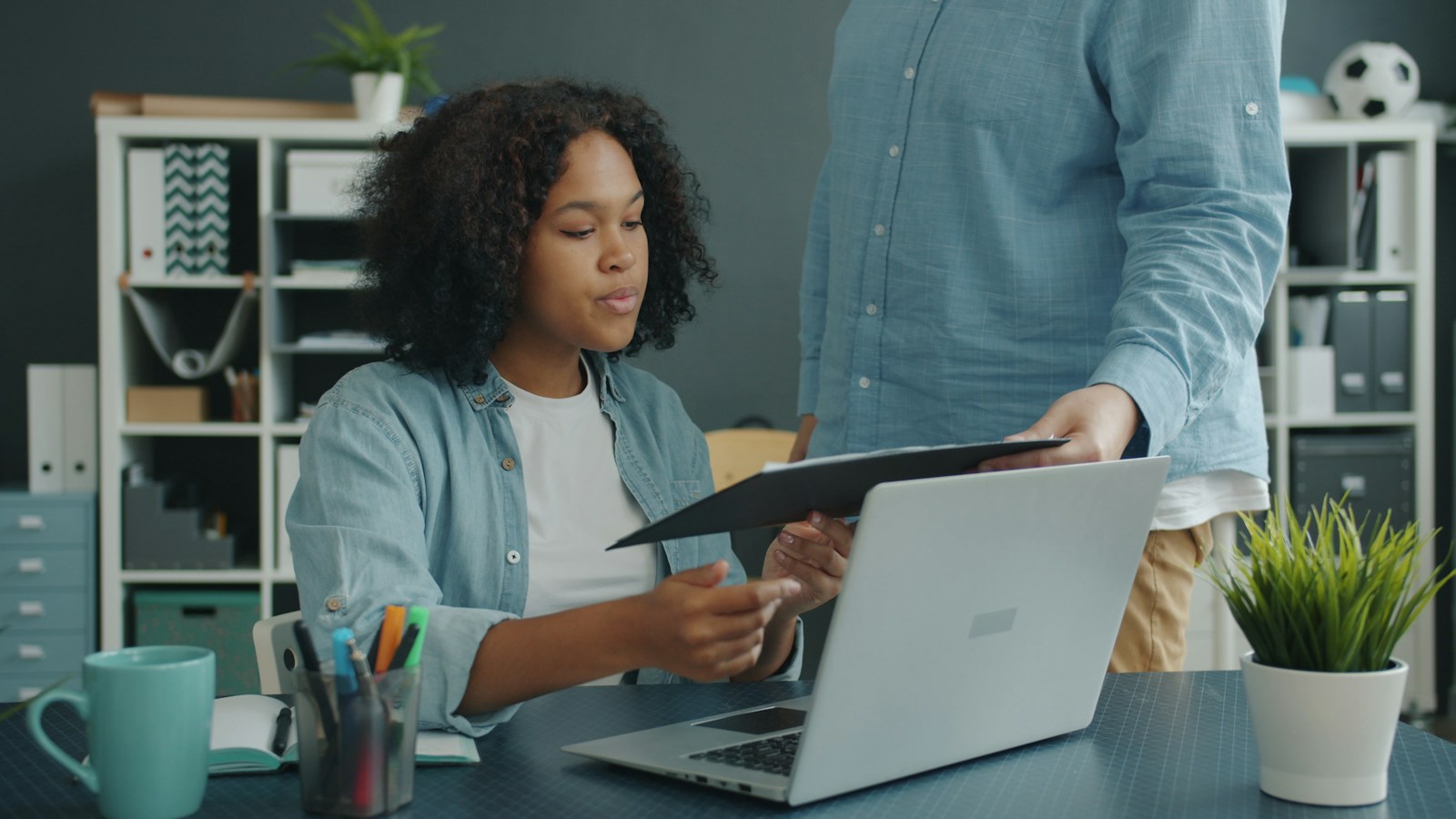 Two staff members reviewing documents next to a laptop at an office desk