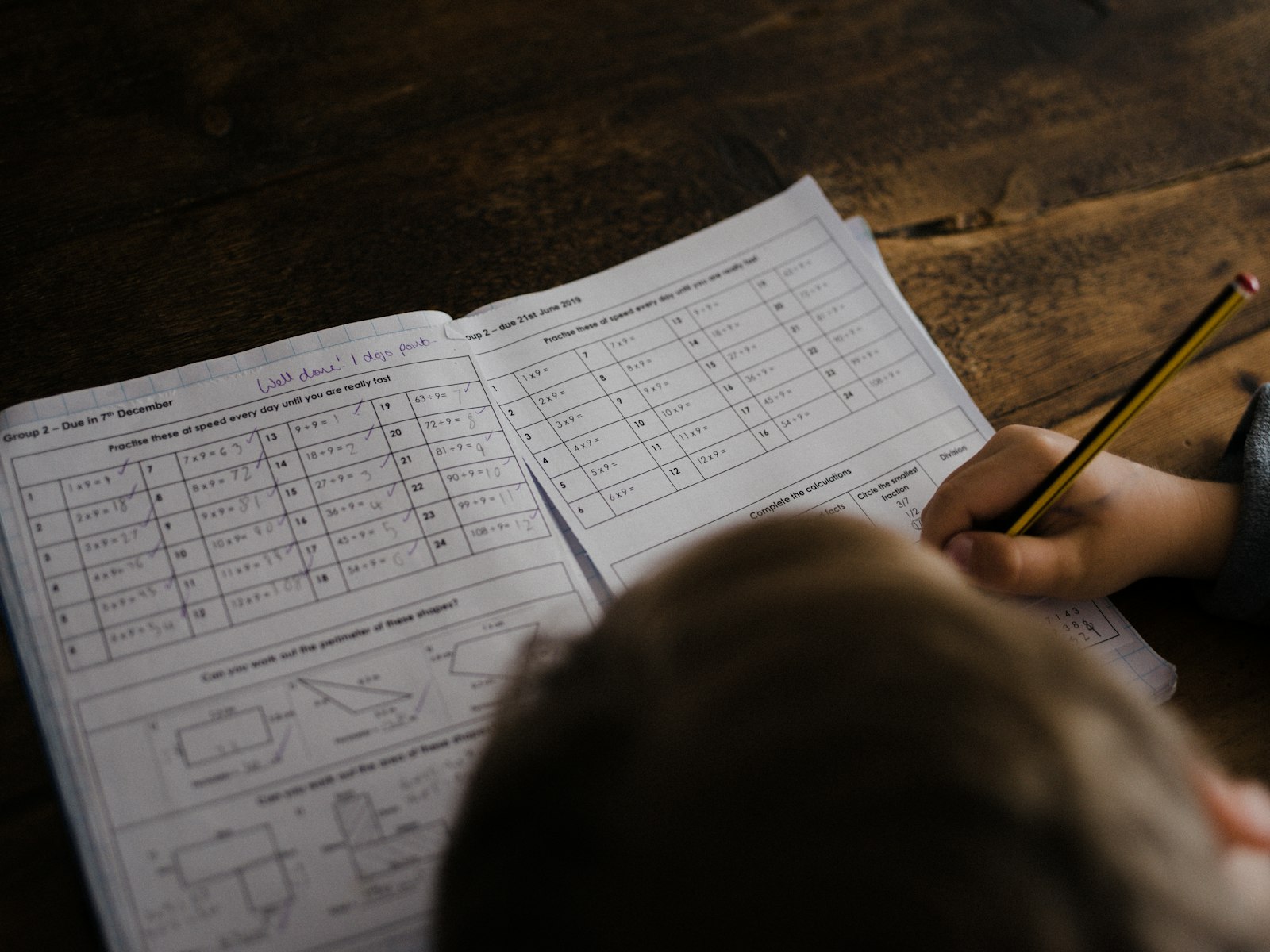 A boy writing in his notebook at a desk without a screen