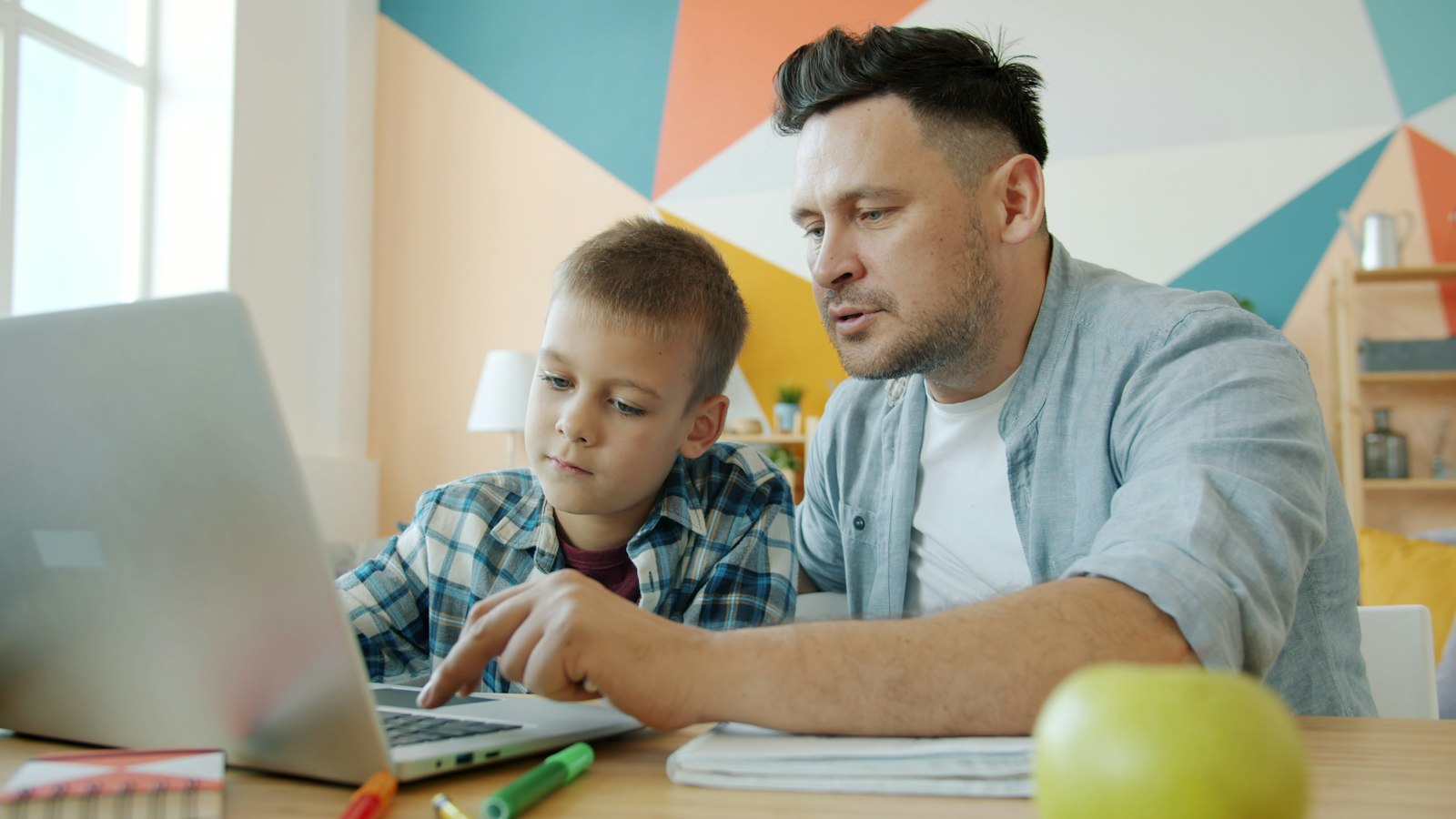 A father and son learning together on a laptop at home