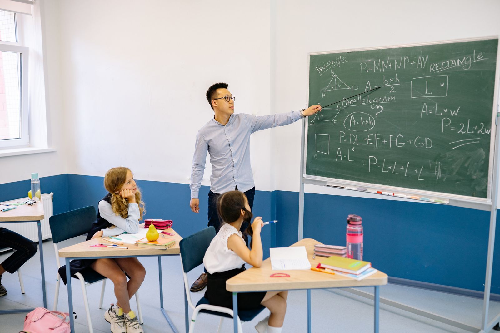 Teacher explaining a geometry problem on the chalkboard to a class.