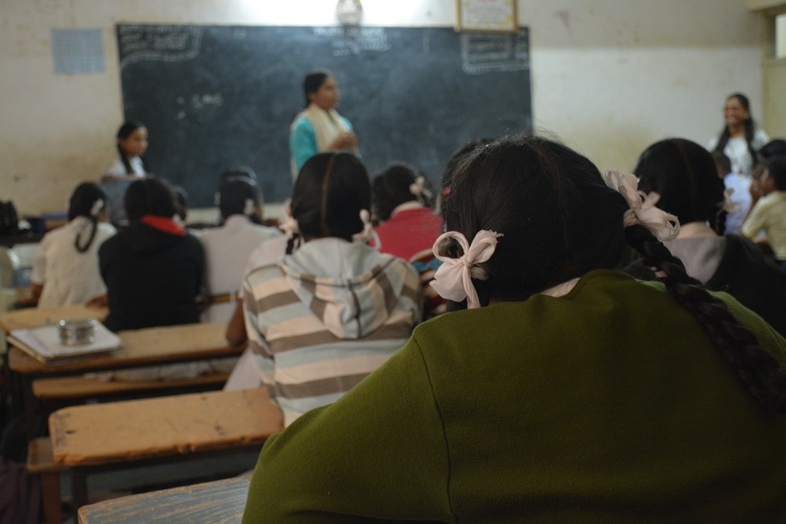 Students in a Bengaluru government school classroom listening to their teacher at the blackboard