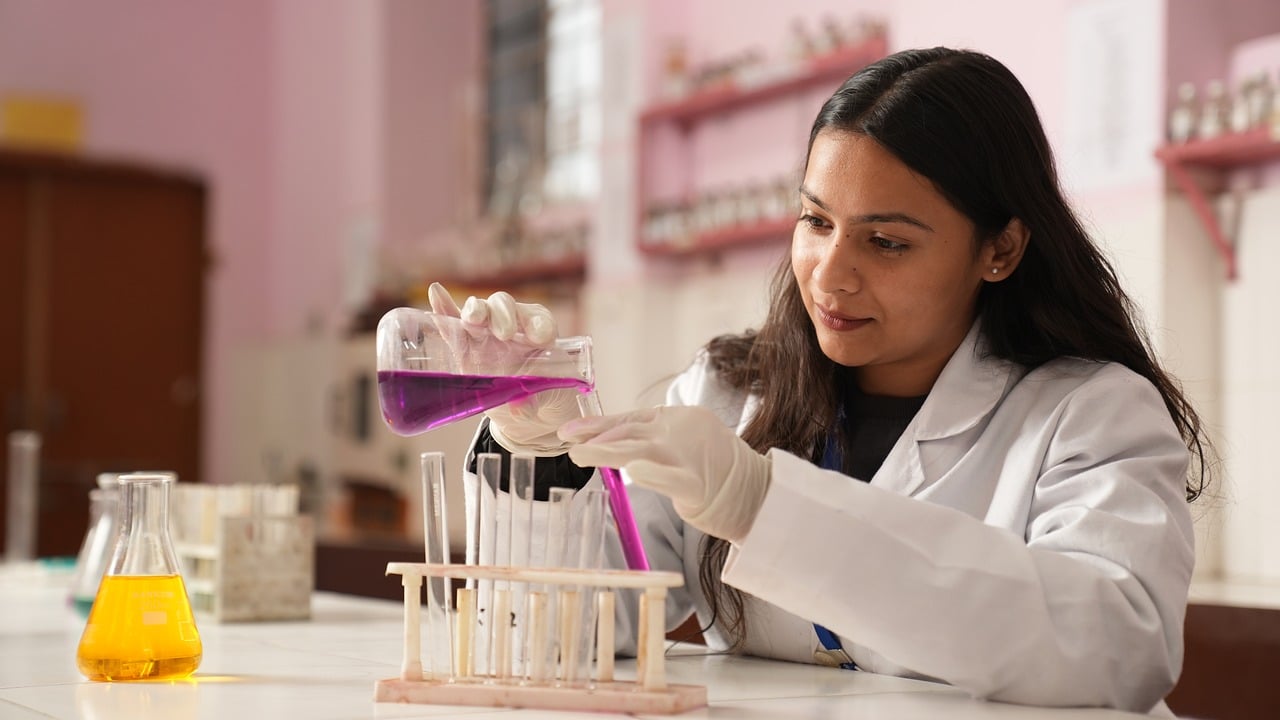 A student in a lab coat doing hands-on lab work.