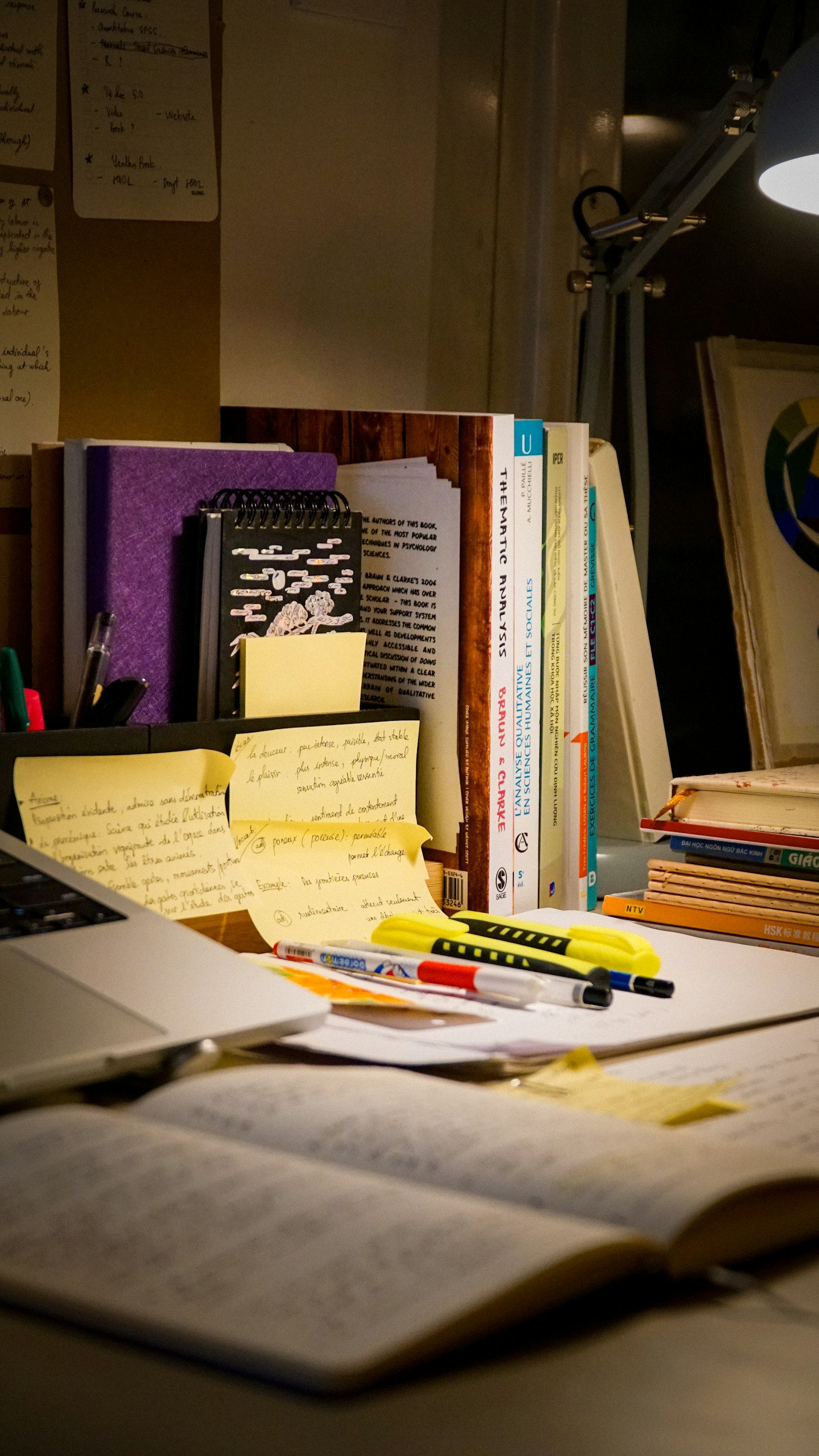 Desk with an open book, laptop and handwritten study notes