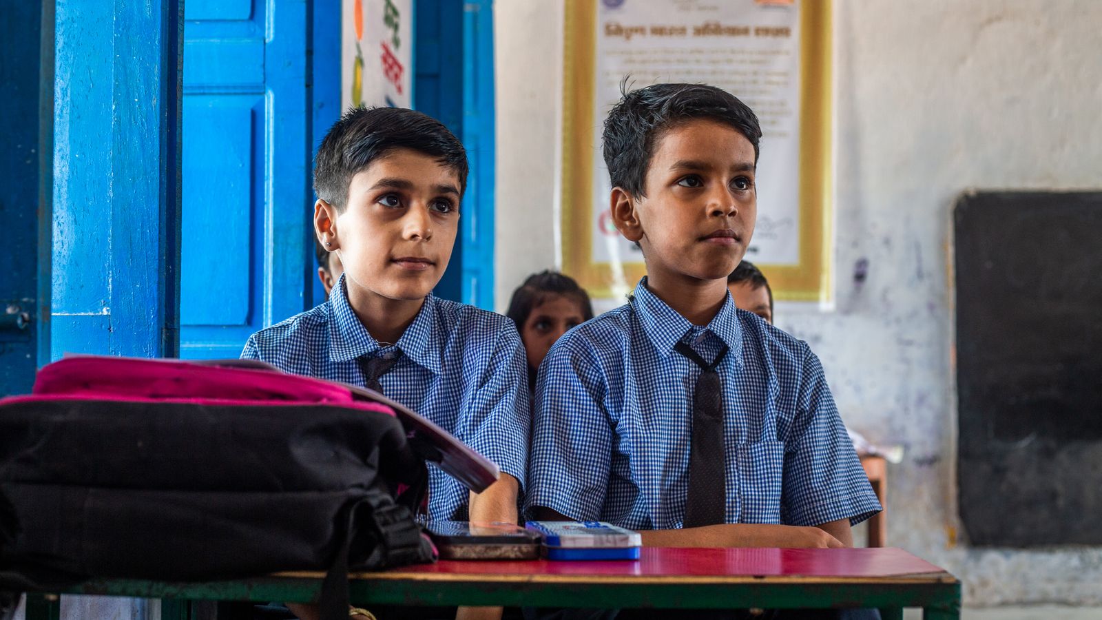 Two Indian schoolboys in uniform listening in class.