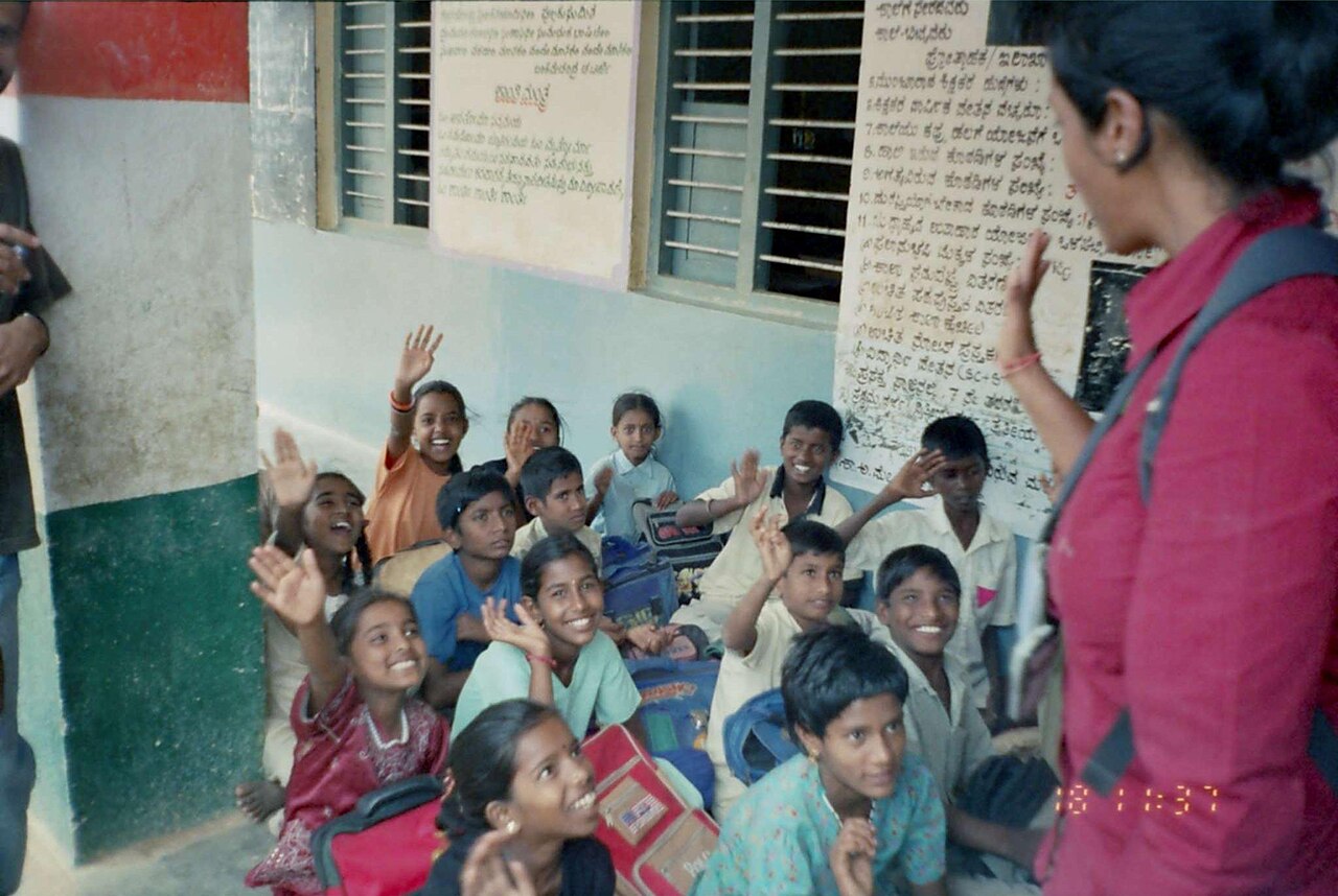 Smiling school students raise their hands to answer a teacher's question