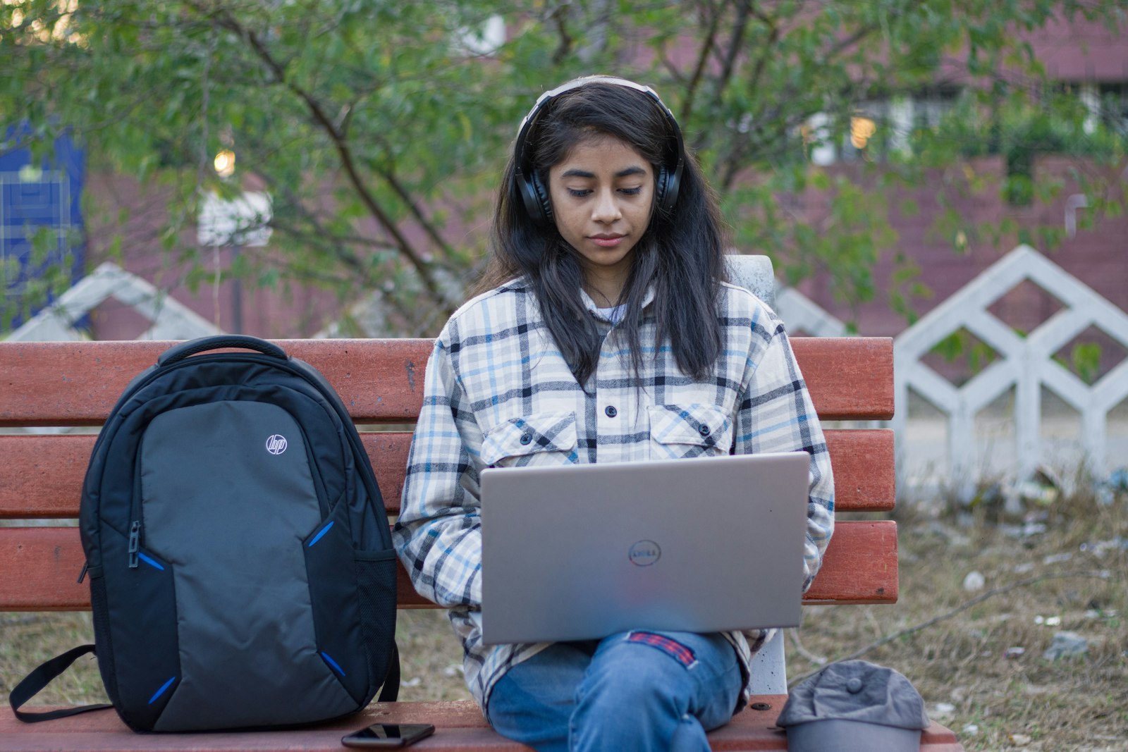 A student sitting on a bench studying on a laptop.