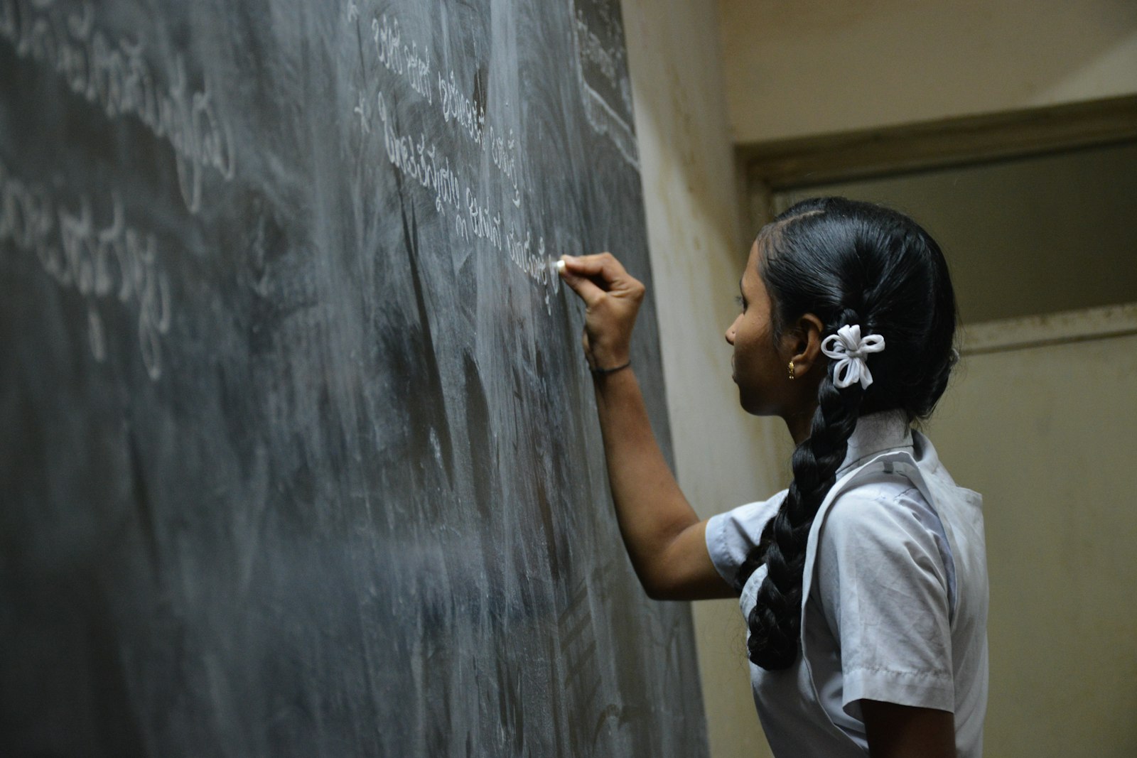 Teacher writing on a chalkboard in a classroom