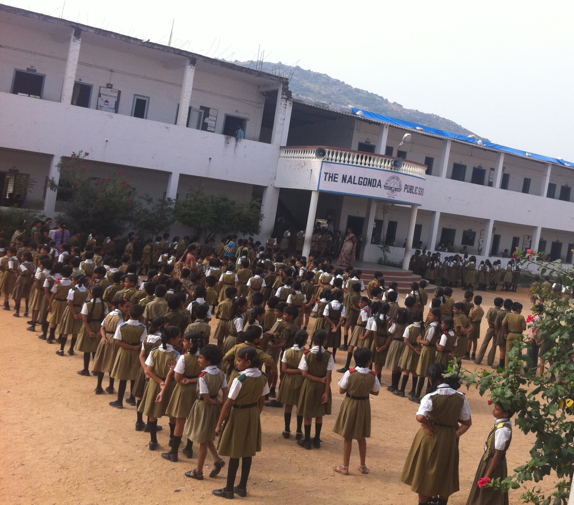 Students in school uniform lined up for morning assembly outside a two-storey school building in India